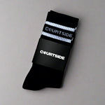 Black socks with white stripe and courtside signature logo shown in packaging