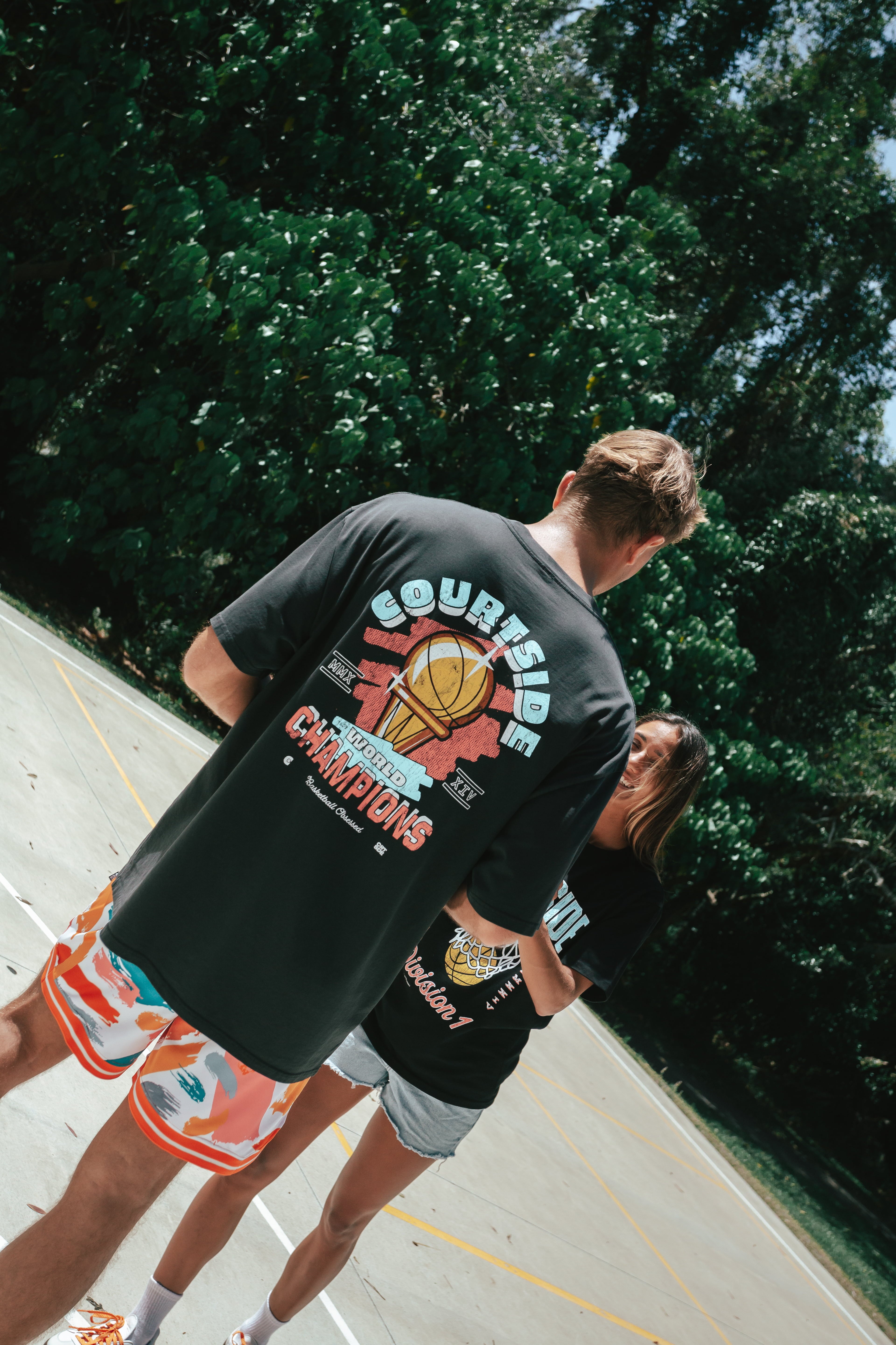 NBL Player Nelson Kahler and Gabi wearing the Courtside Champs Tee in Faded Black colour.