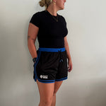 Female basketball player wearing the Courtside Black & Royal Blue DPOYW basketball short in women's cut showing details