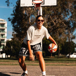 Courtside Black basketball shorts on NBL1  basketball player Ash Frampton with white large letters across front CRT SDE short for Courtside with Teal detailing.