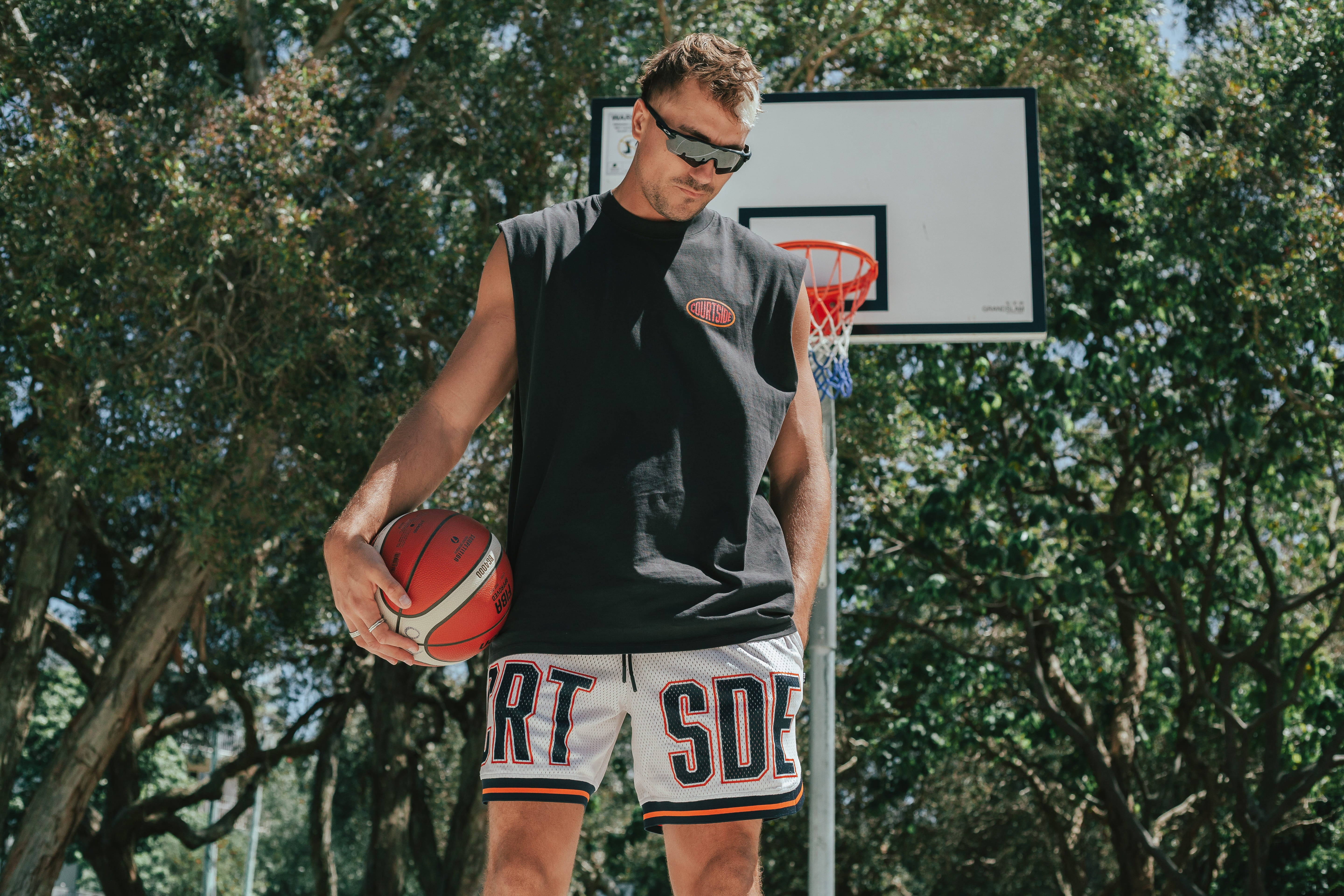 Courtside DPOY basketball shorts with CRT SDE letters in bold across front leg shown on Nelson Kahler NBL player holding basketball on hip