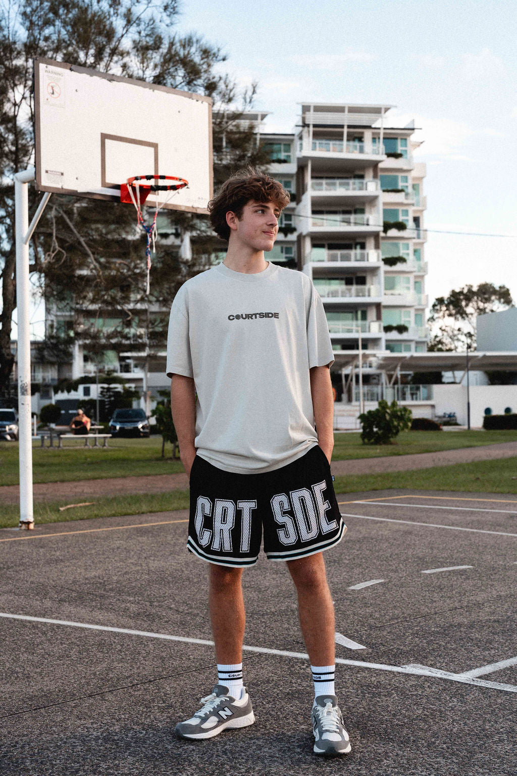 young male basketball player wearing the Koby tee in faded bone and courtside basketball shorts and socks.