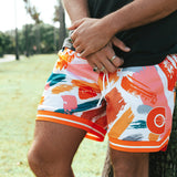 Nelson Kahler NBL player wear orange and white coloured patterned shorts leaning up against palm tree