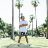 Courtside ROTY basketball shorts shown on Nelson NBL player with white hooper tee with red print, standing cross armed with palm trees