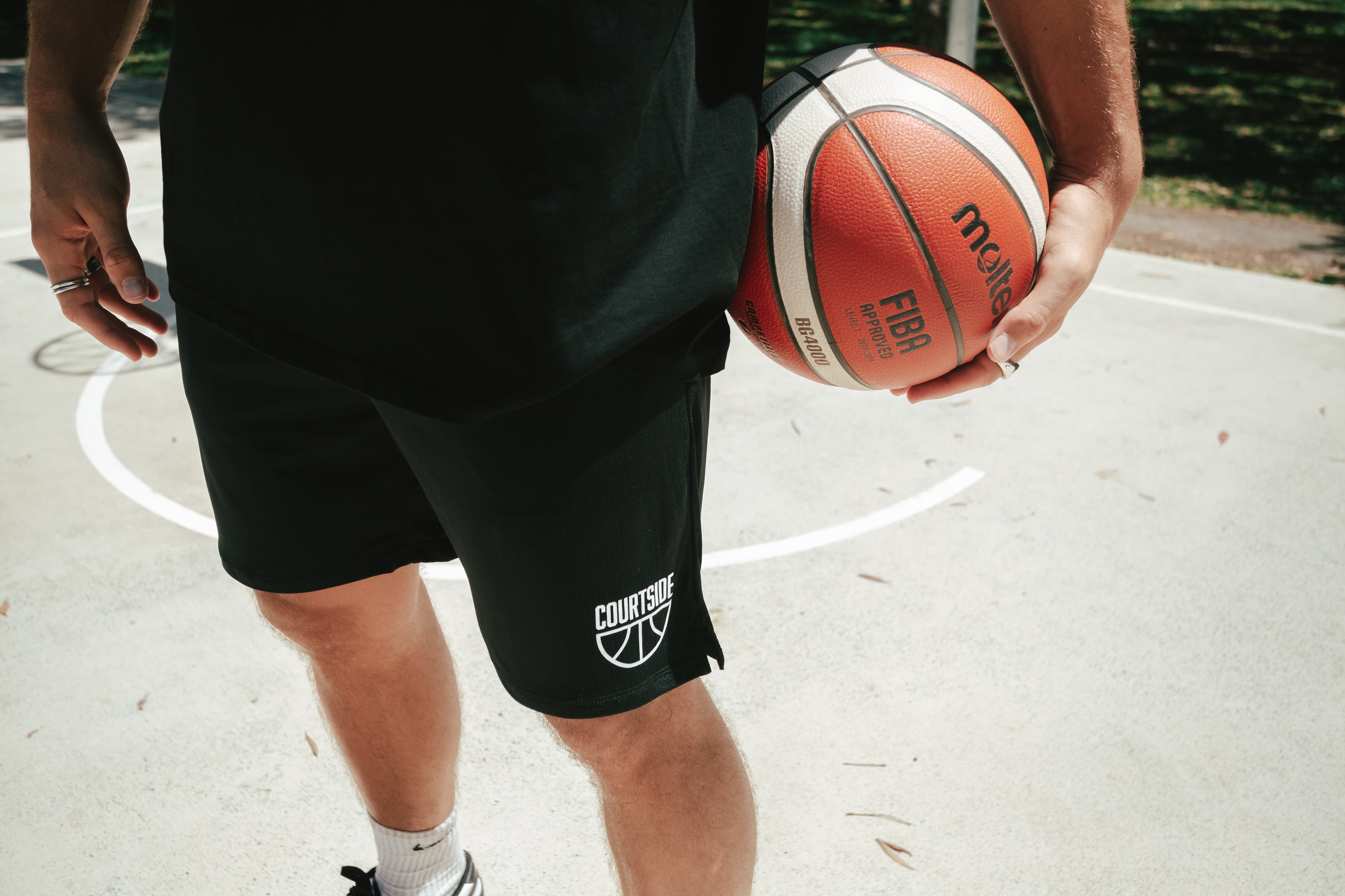 Black basketball netted shorts, narrow, long legged, traditional short with white half ball courtside logo on bottom left leg front.