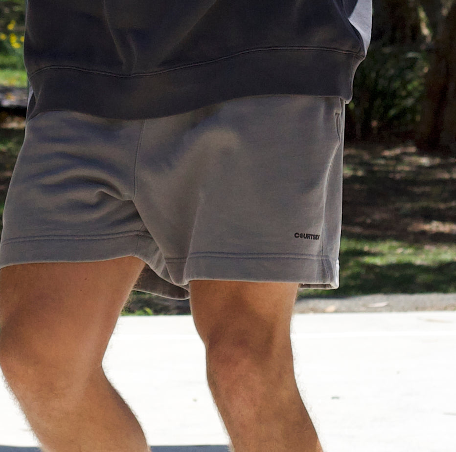 dark grey basketball shorts shown on basketball player with subtle black logo on left leg