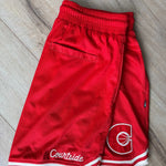 Red basketball shorts with a logo and 'Courtside' text on a wooden floor.