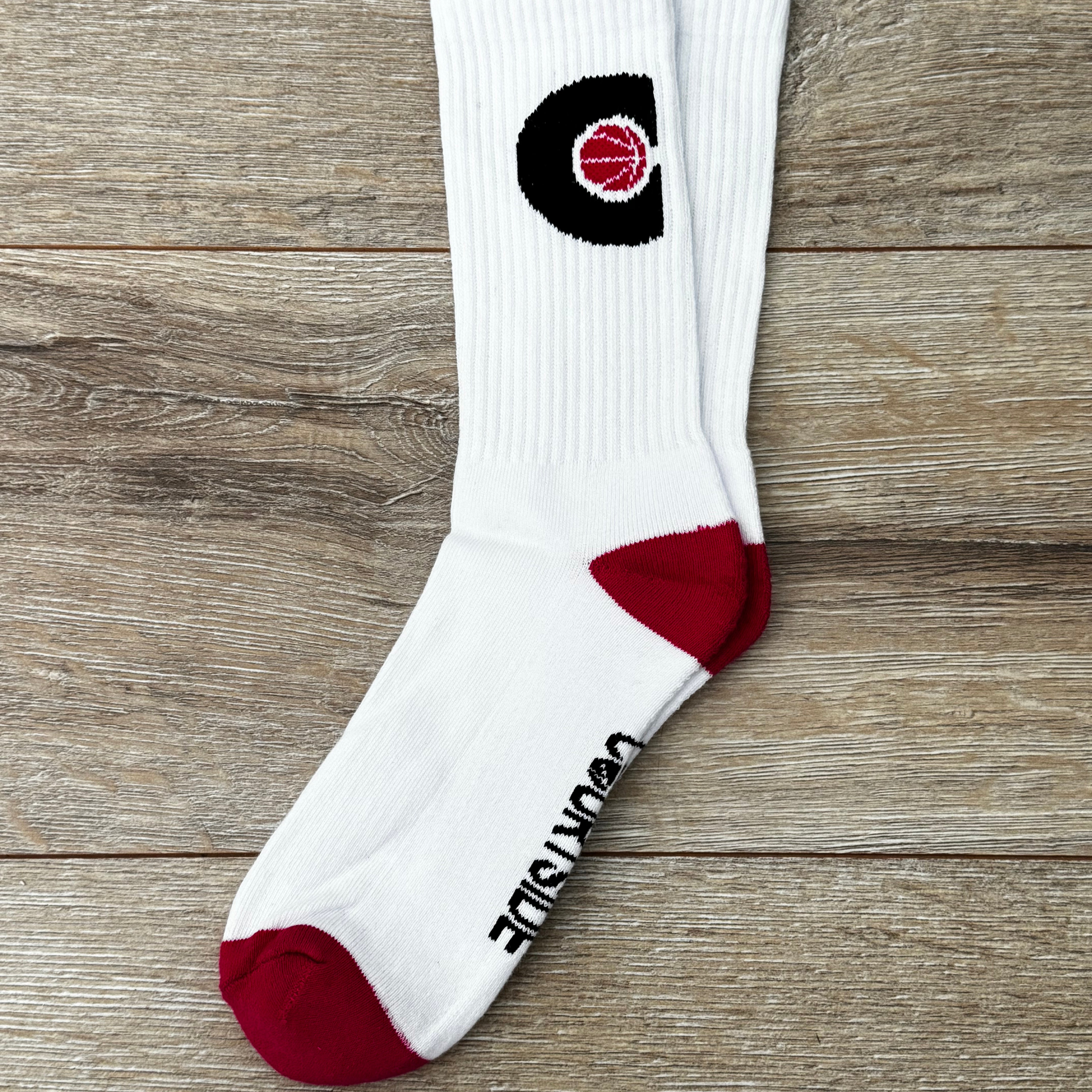 Pair of white socks with pink ball in a black C hoop logo, pink toes and heels shown flat
