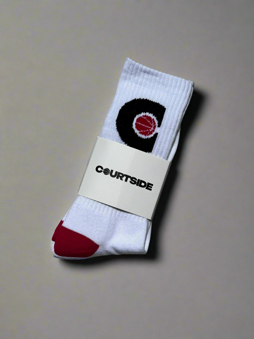Pair of white socks with pink ball in a black C hoop logo, pink toes and heels shown in packaging