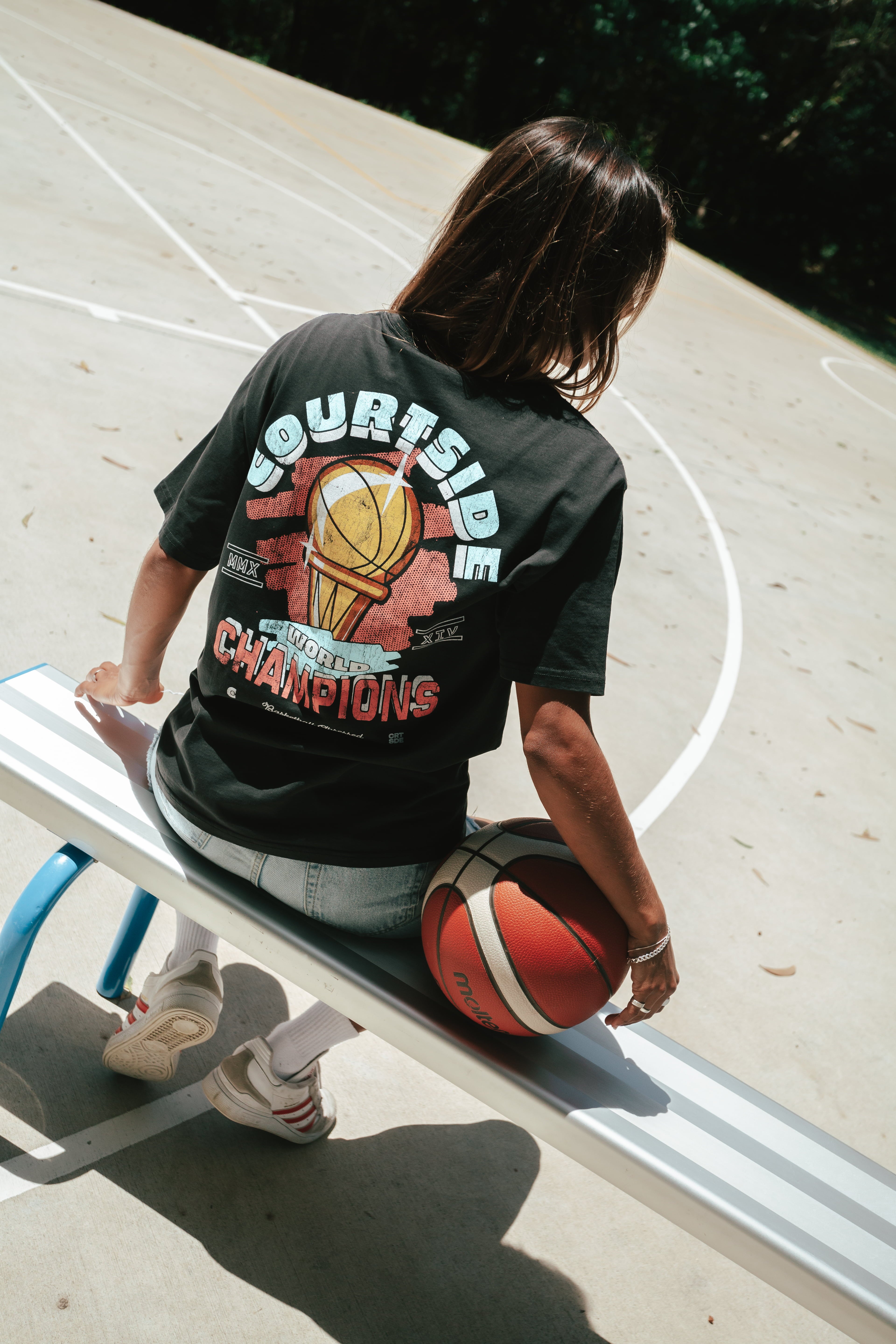Gabi wearing the Courtside Champs Tee in Faded Black colour.