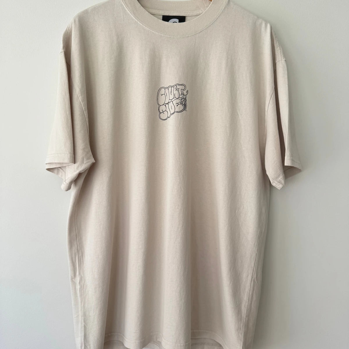 Bone t-shirt with a centre chest logo on a wooden hanger against a white background