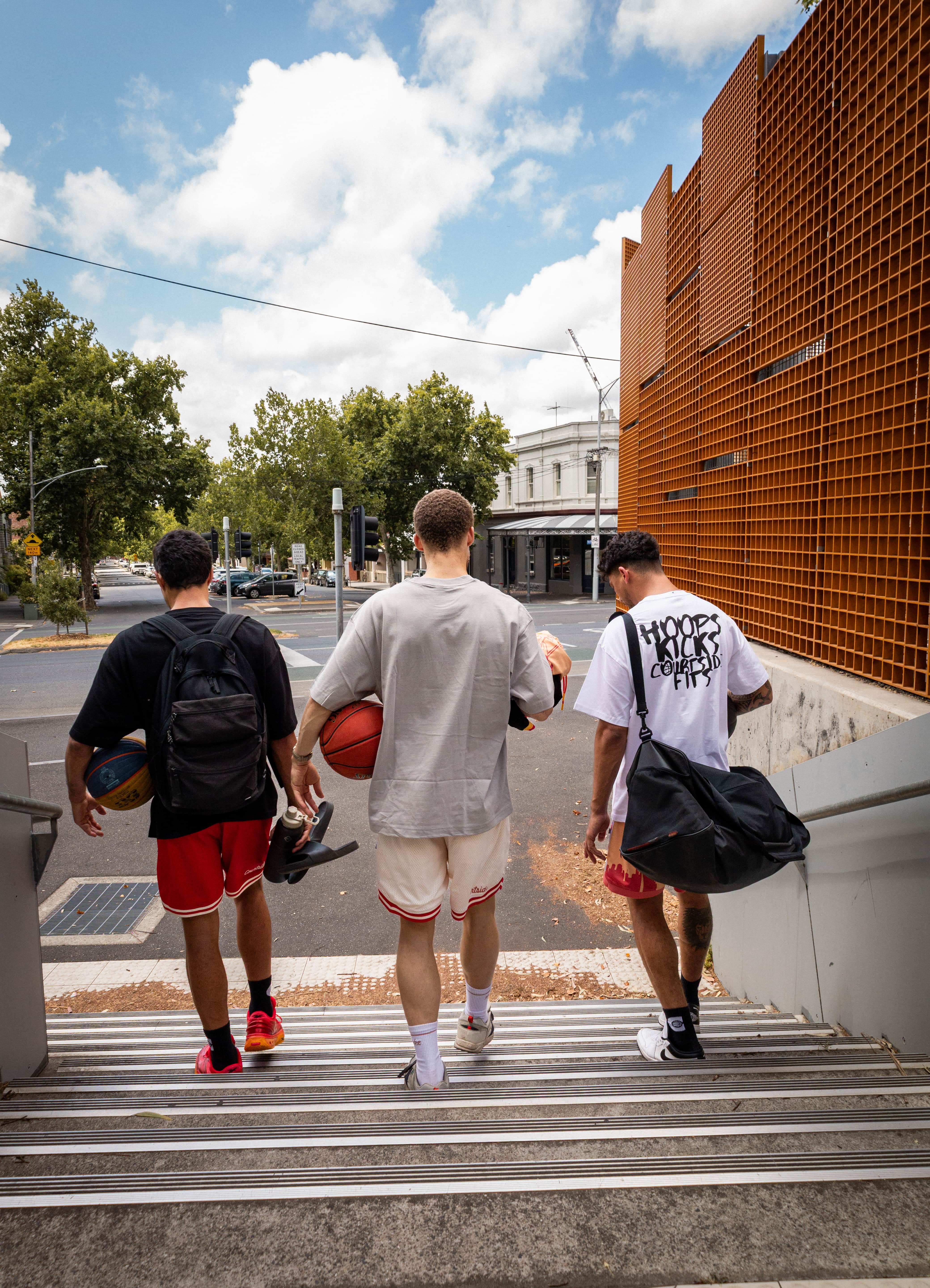 Three young men walking up a set of stairs on a city street in Melbourne.