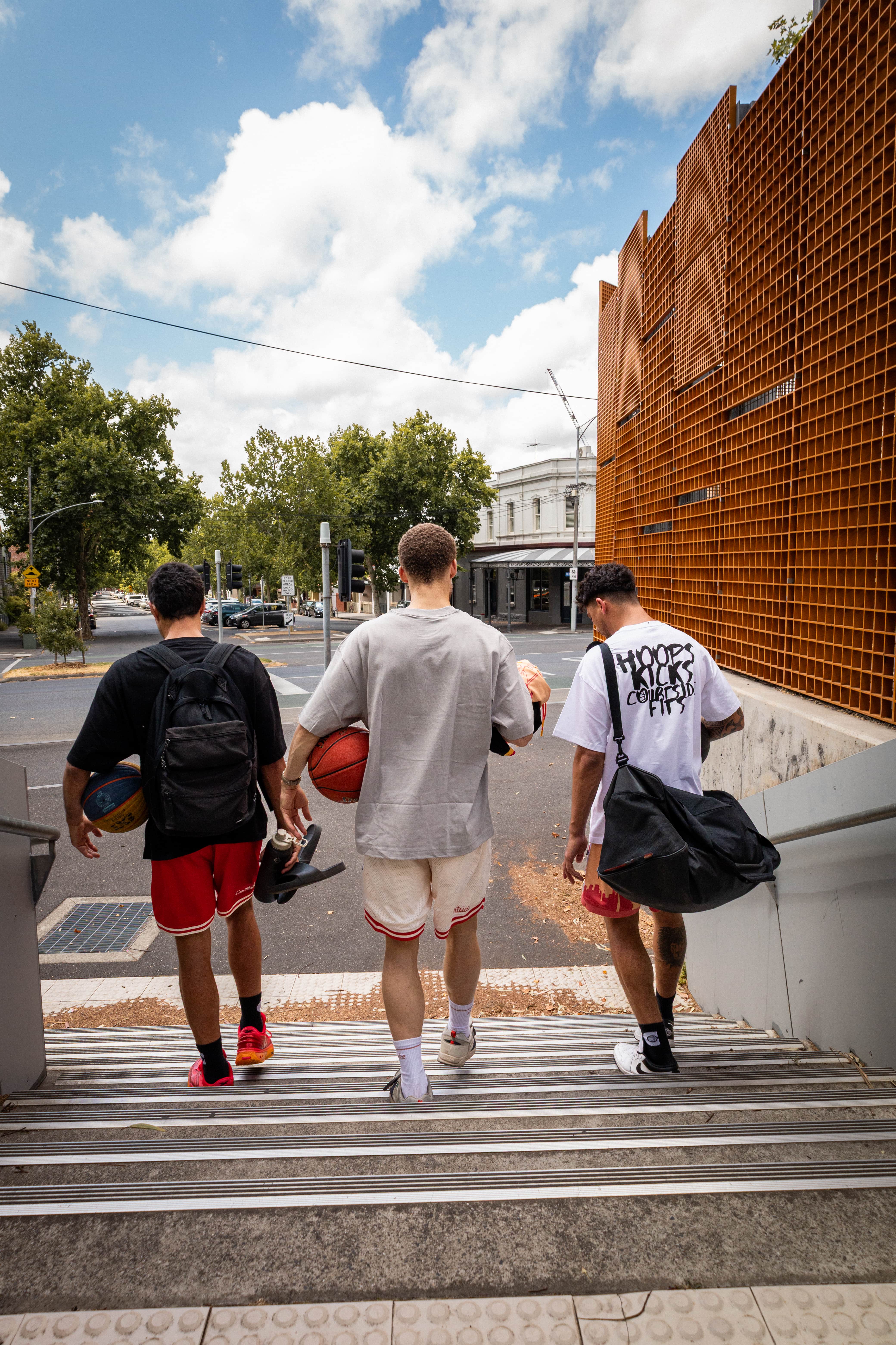 Three young men walking up a set of stairs on a city street in Melbourne.