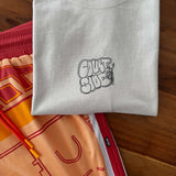 Folded bone t-shirt with a black logo on a wooden surface