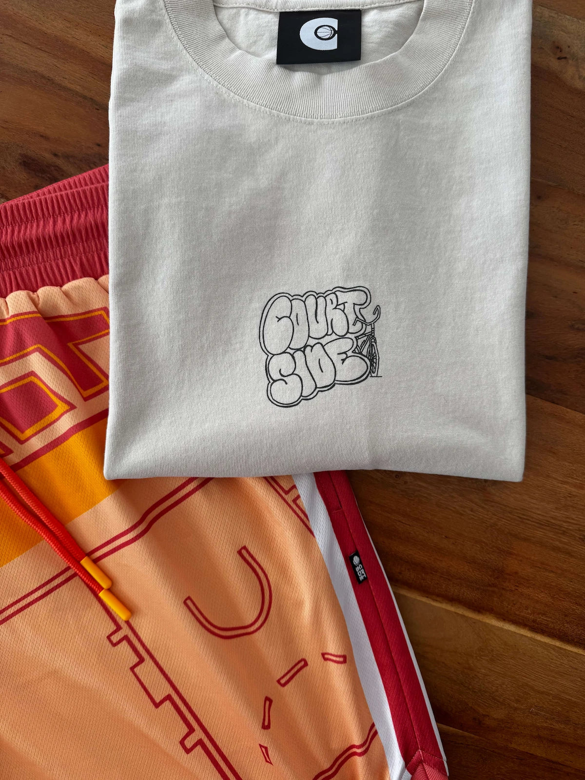 Folded bone t-shirt with a black logo on a wooden surface