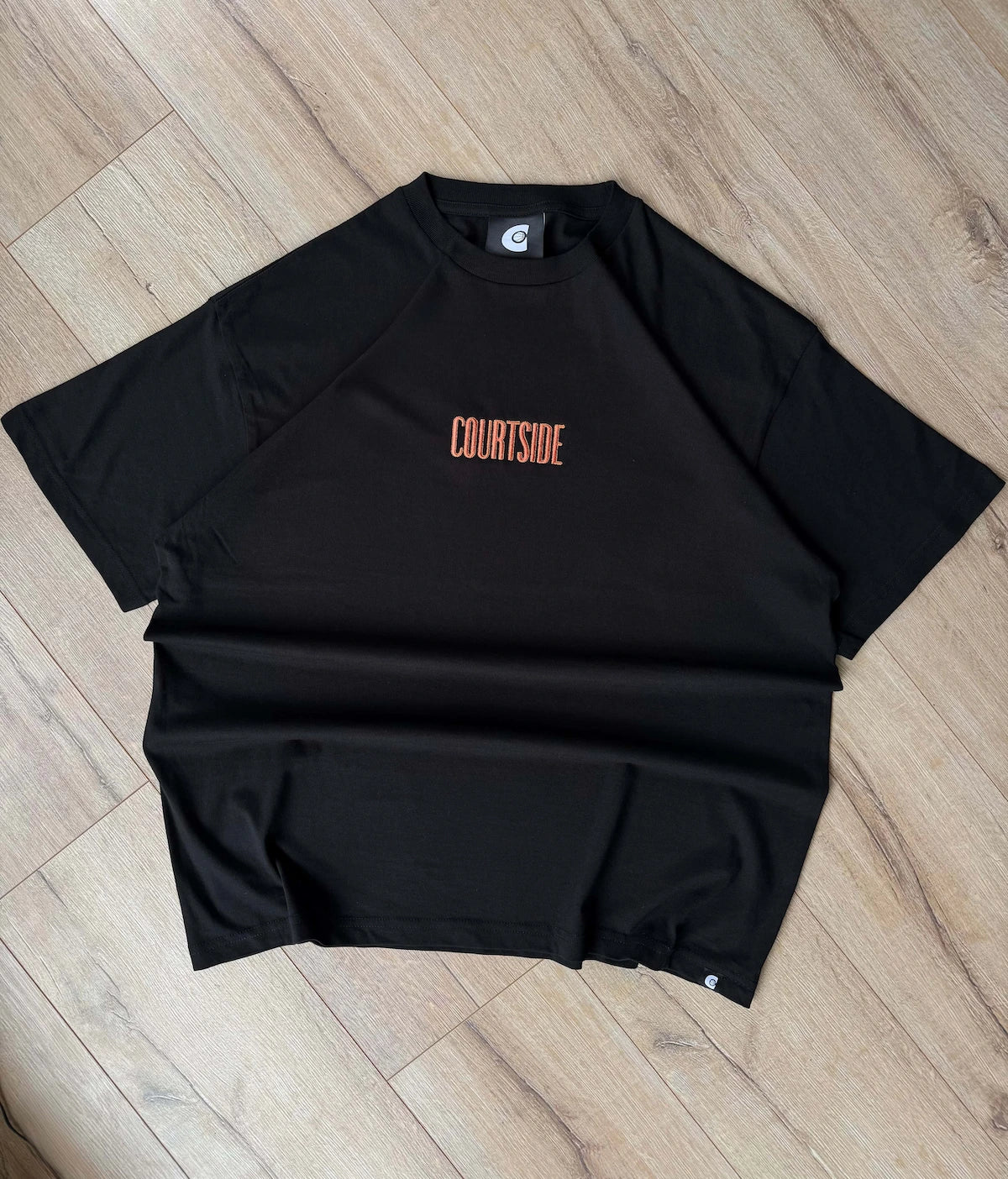 Black t-shirt with 'COURTSIDE' text on a wooden floor