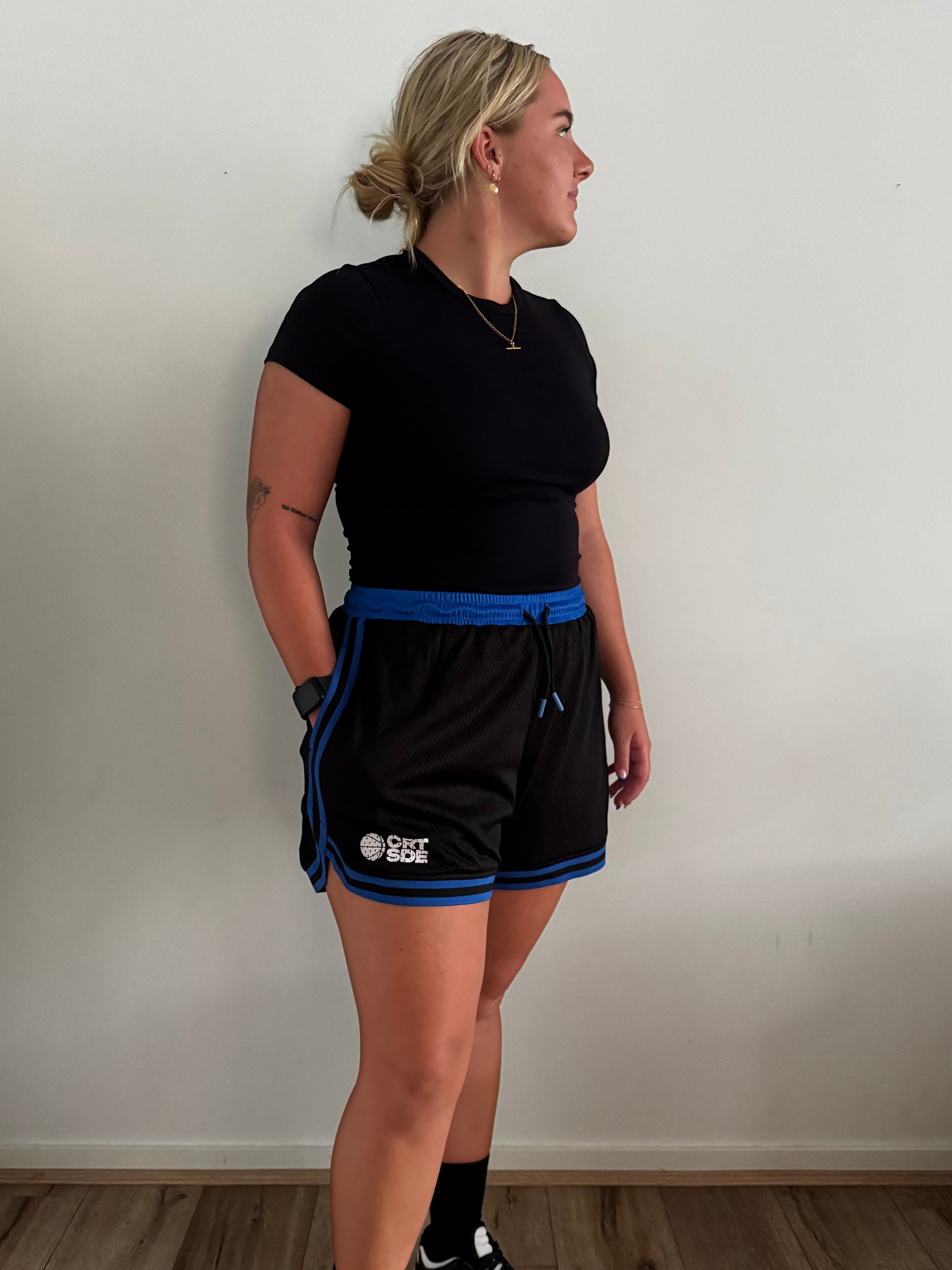 Female basketball player wearing the Courtside Black & Royal Blue DPOYW basketball short in women's cut showing details