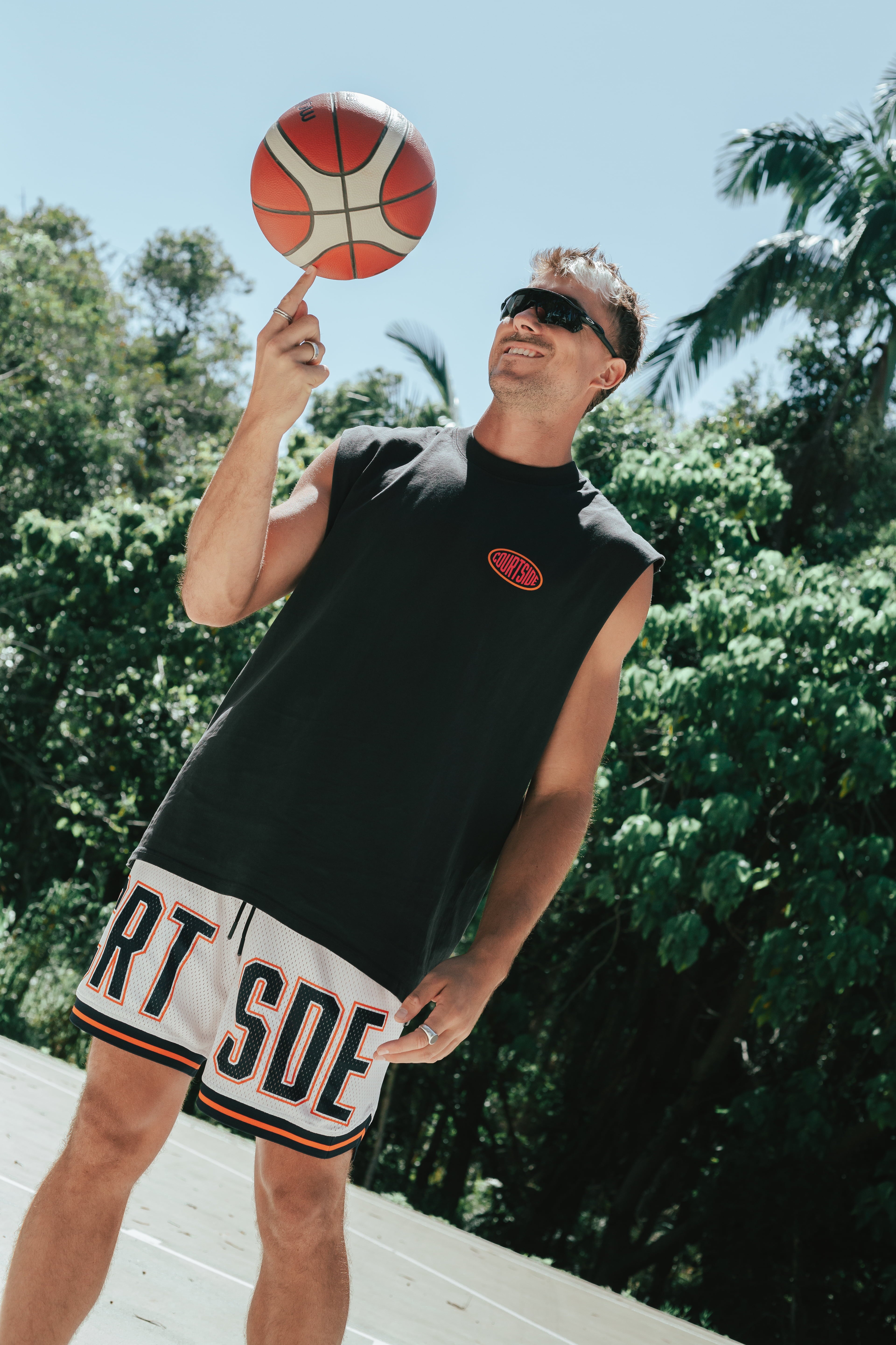 Courtside DPOY basketball shorts with CRT SDE letters in bold across front leg shown on Nelson Kahler NBL player spinning basketball on finger