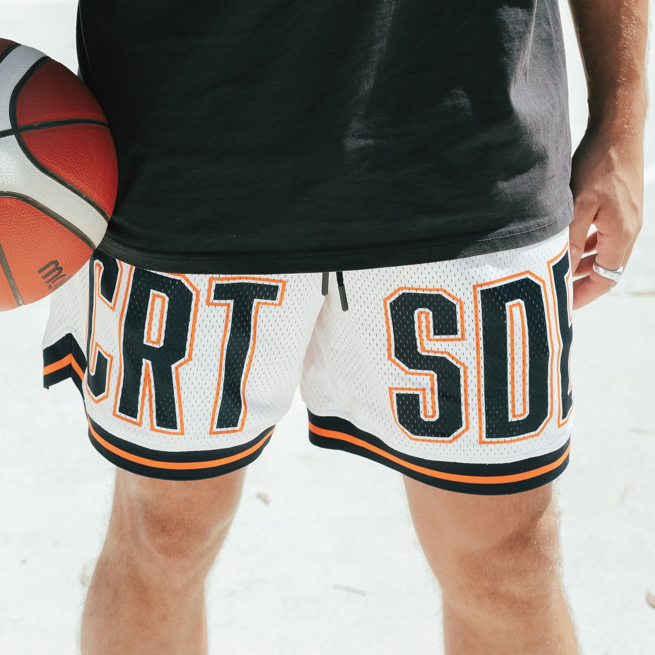 Courtside DPOY basketball shorts with CRT SDE letters in bold across front leg shown on Nelson Kahler NBL player holding a basketball