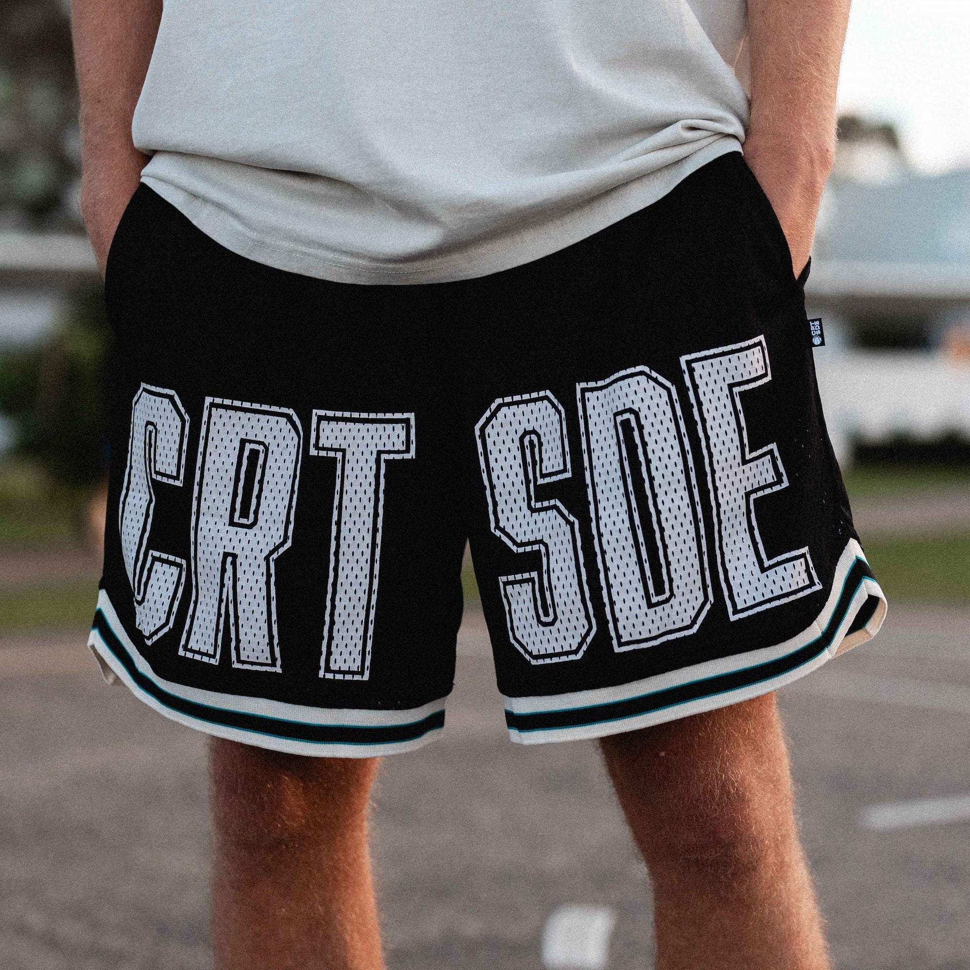 Courtside Black basketball shorts on Louis Lauret elite junior basketball player with white large letters across front CRT SDE short for Courtside with Teal detailing.