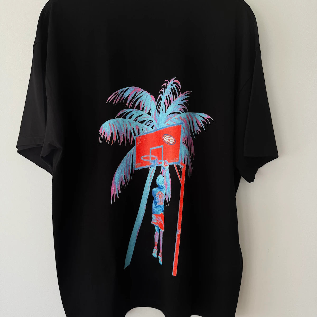 Black t-shirt with colorful palm tree design on a white background