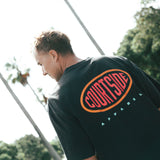 A person wearing a black crew neck T-shirt with the brand logo 'Courtside' on the back.