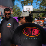 Two men standing on a basketball court in Melbourne with one wearing a 'Courtside Apparel' shirt.
