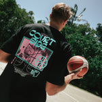 A person wearing a black Vibes Tee with a basketball and text graphic on it, standing outdoors.