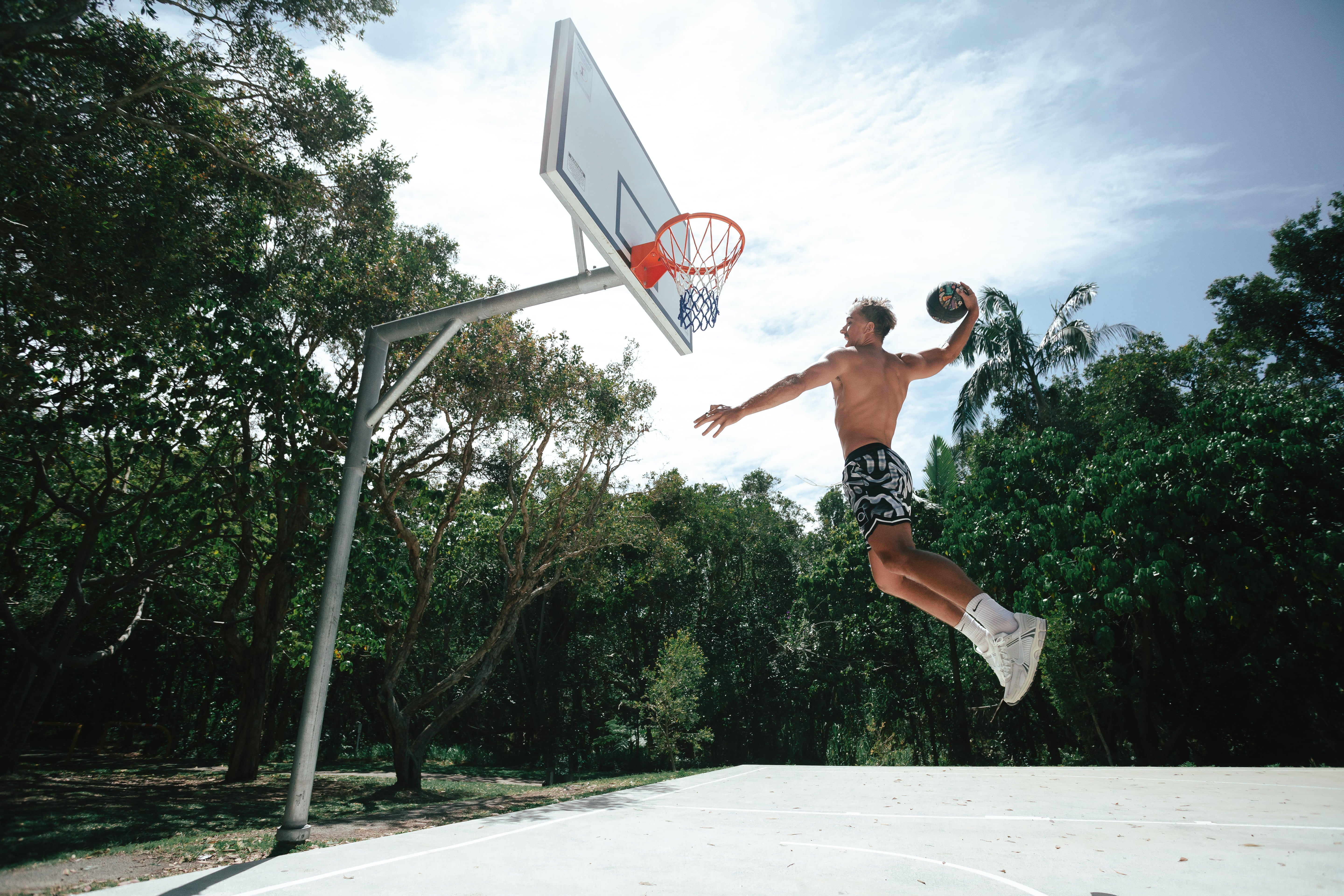 Nelson Kahler basketball player elevated about to slam dunk a basketball showing the performance and passion for the game wearing our ROTY basketball shorts in black and white